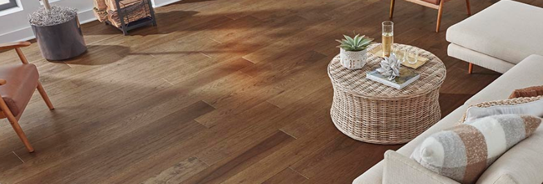 Rich brown wood-look Mohawk engineered hardwood floors add coziness to a living room with white and light beige décor.